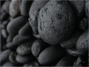 Smooth black pebbles stacked closely together.