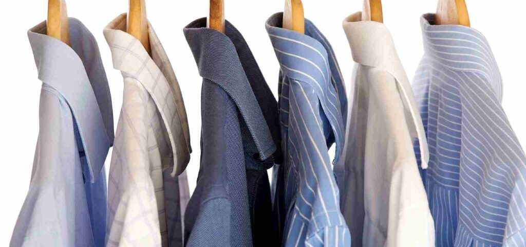 Men's dress shirts hanging on wooden hangers.