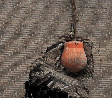 Wrecking ball demolishing a brick wall.
