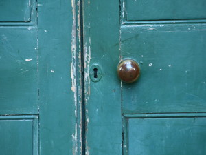 Old green door with keyhole and knob.
