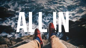 Feet on cliff with "All In" text.