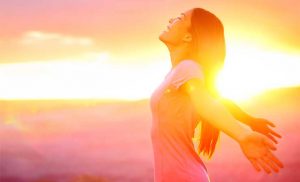 Woman enjoying sunrise with open arms.