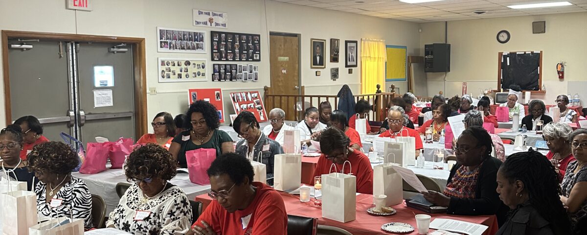 People gathered at an indoor event with tables and gift bags.